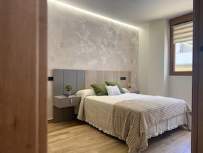 A bedroom with a bed, bedside tables, and a nightstand. - Flower Beach Helgueras 5 - 6095 (Noja)