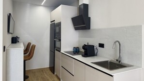 Ett modernt kök med en inbyggd ugn, en kaffemaskin och en diskho.