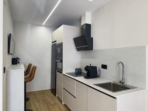 Een moderne keuken met een ingebouwde oven, een koffieapparaat en een spoelbak.