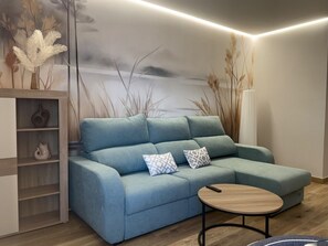 Een moderne woonkamer met een modulaire bank, een ronde salontafel en een decoratieve wanddecoratie.