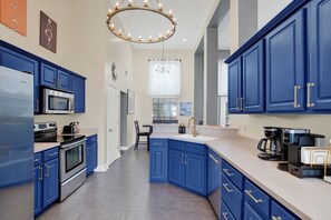 A modern kitchen with blue cabinets, stainless steel appliances, and a large island. - Savannah Family Hub: Game RM, Screened Porch & Work From Home, 15 mins Downtown (Pooler)