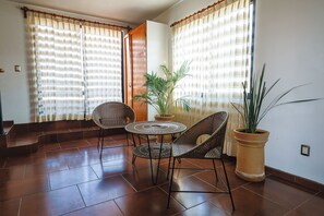 A room with a tiled floor, two wicker chairs, a small round table, and a potted plant. - MaryFer House (San Juan Bautista la Raya)