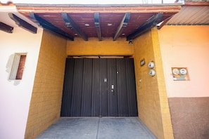 Una porta de garatge tancada amb un teulat metàl·lic a dalt, una paret de maó i una petita finestra a l'esquerra.