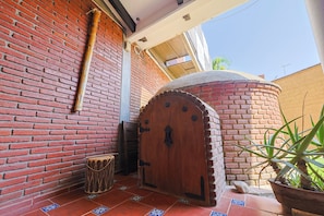 A brick wall, a wooden door, a tiled floor, and a potted plant.