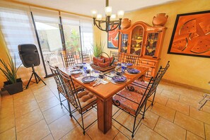 Un comedor con una mesa de madera, sillas de metal y un armario con puertas de vidrio.