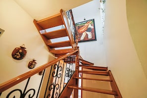 Una escalera de madera con barandilla negra, un cuadro en la pared y un pequeño objeto decorativo en la pared.