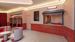 Des toilettes d’hôtel avec des murs carrelés en rouge et beige, un miroir et un panneau indiquant des informations dans une langue étrangère.