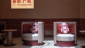 Un espace détente avec deux chaises, une table et un panneau mural affichant des caractères chinois.