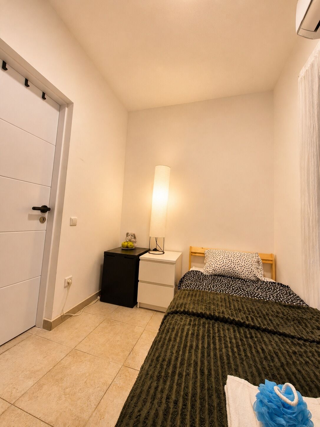 A bedroom with a bed, bedside table, lamp, and a wardrobe.