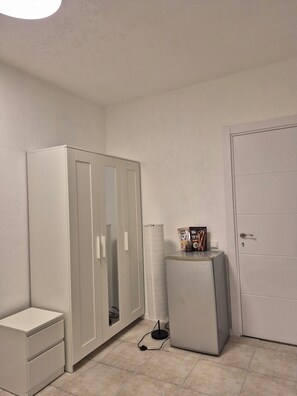 A room with a wardrobe, a small desk, a cabinet, a door, and a box on the floor. - The Lemon House (Tel Aviv)