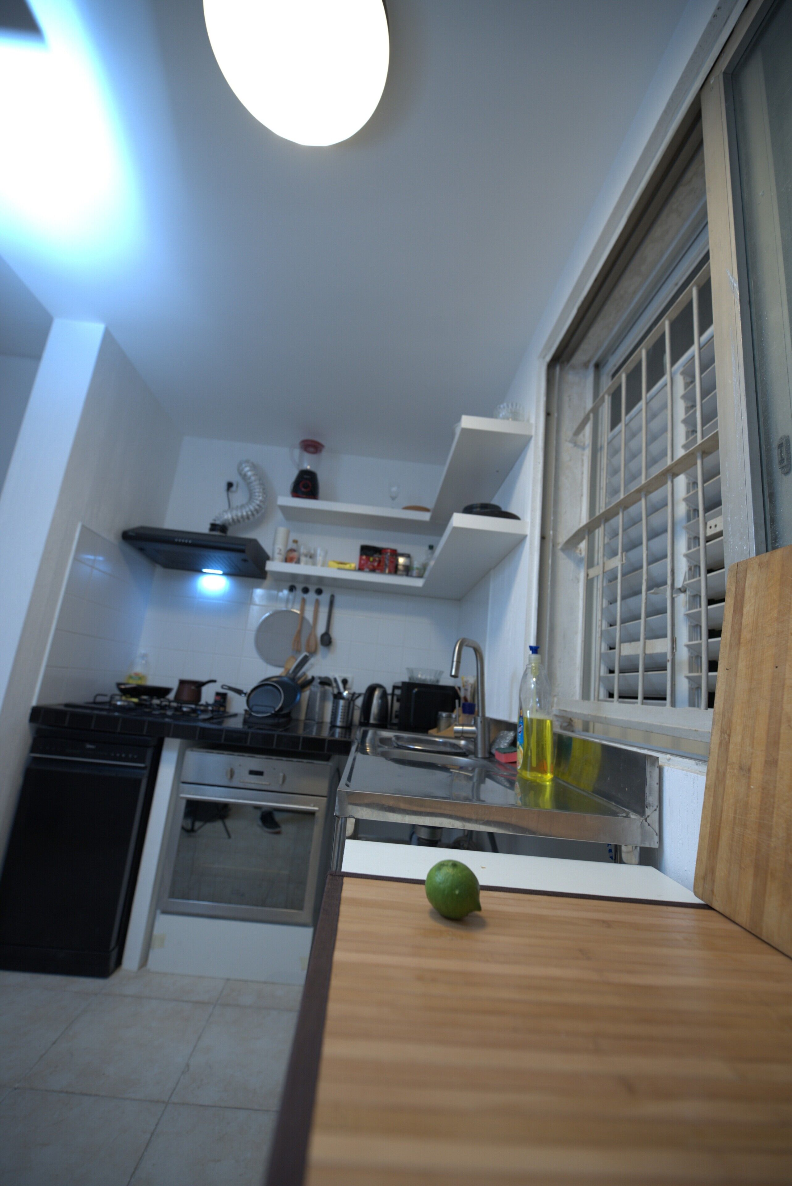 A compact kitchen with a gas stove, a sink, and a window with blinds.