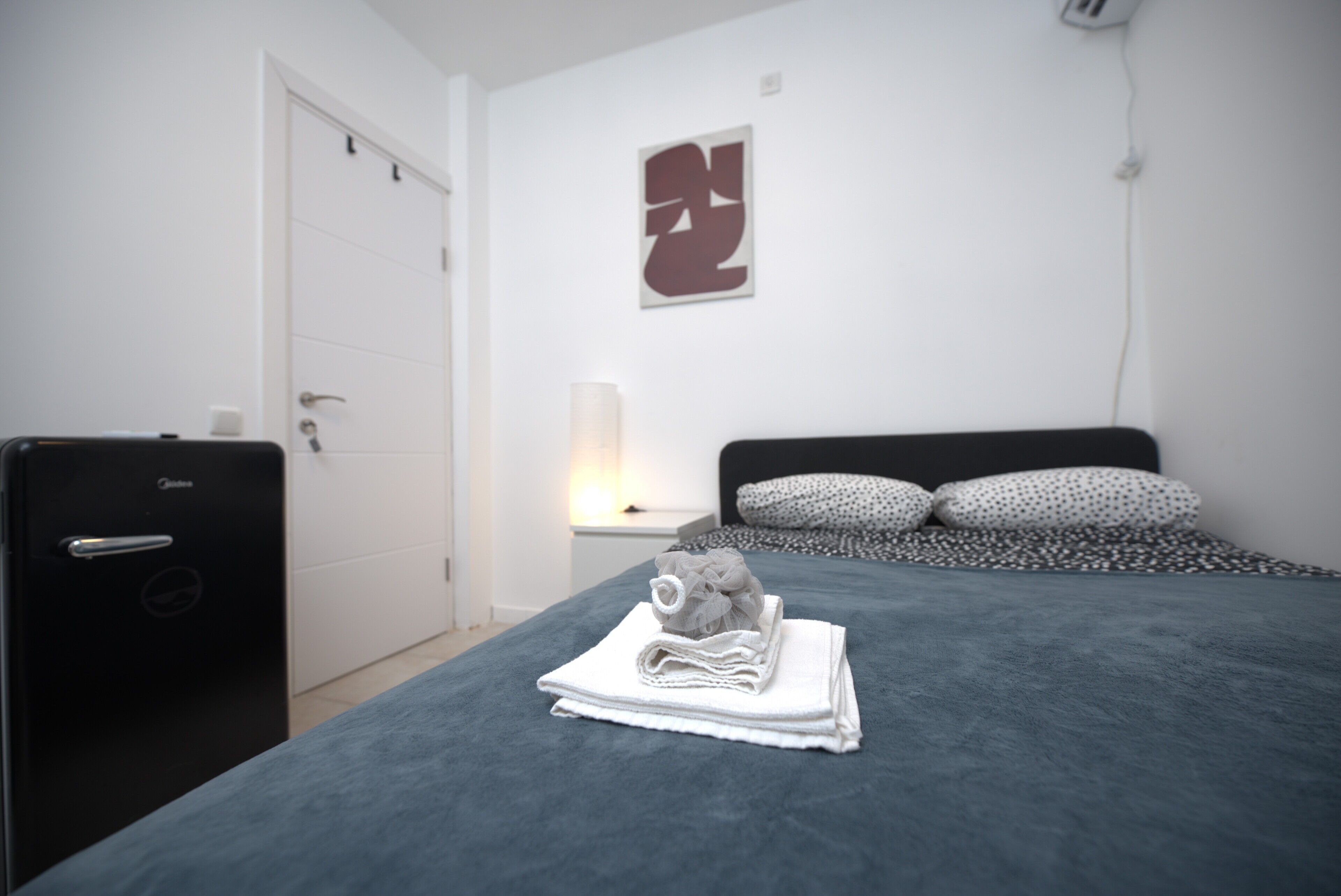 A room with a bed, a desk, and a door.
