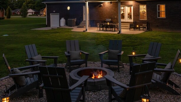 A backyard with a fire pit, outdoor seating, and a covered patio area.