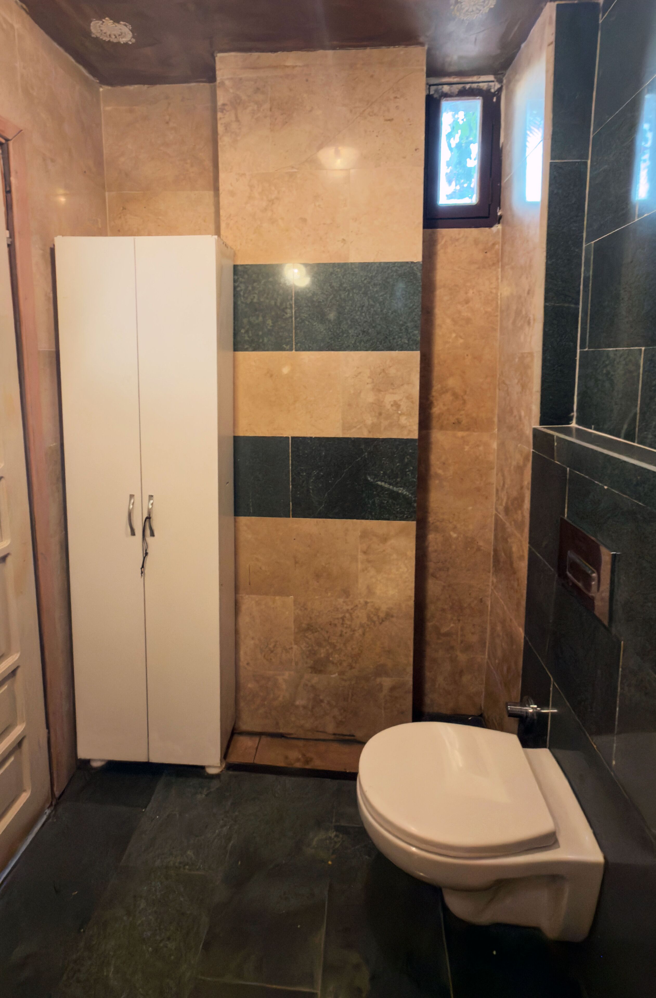 Ein Badezimmer mit Toilette, Schrank und Duschbereich.
