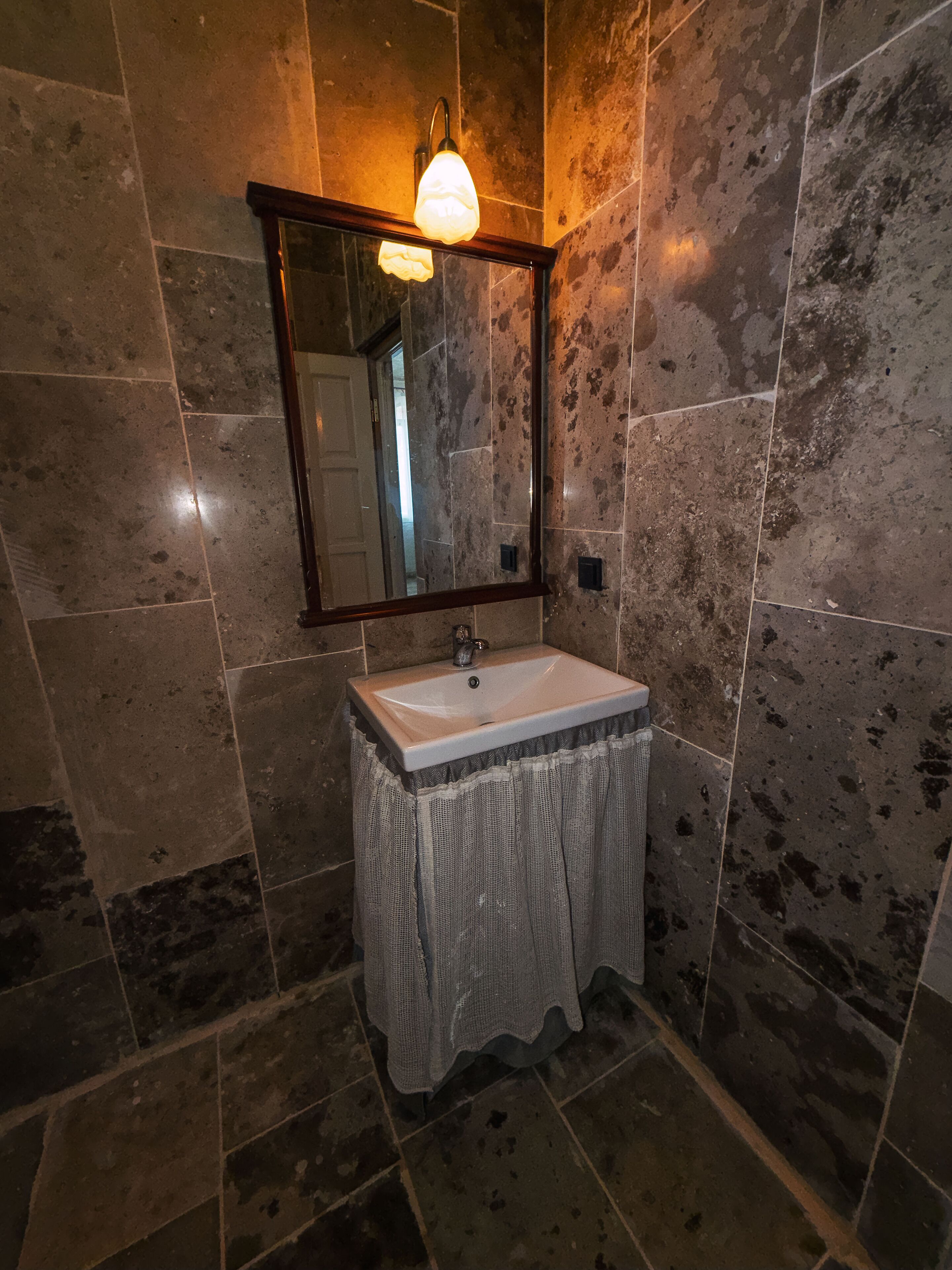 A bathroom with a sink, mirror, and light fixture.