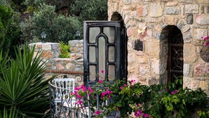 A stone building with a balcony, a wrought iron chair, and bougainvillea flowers. - Nurmahal Art & Heritage (Bodrum)