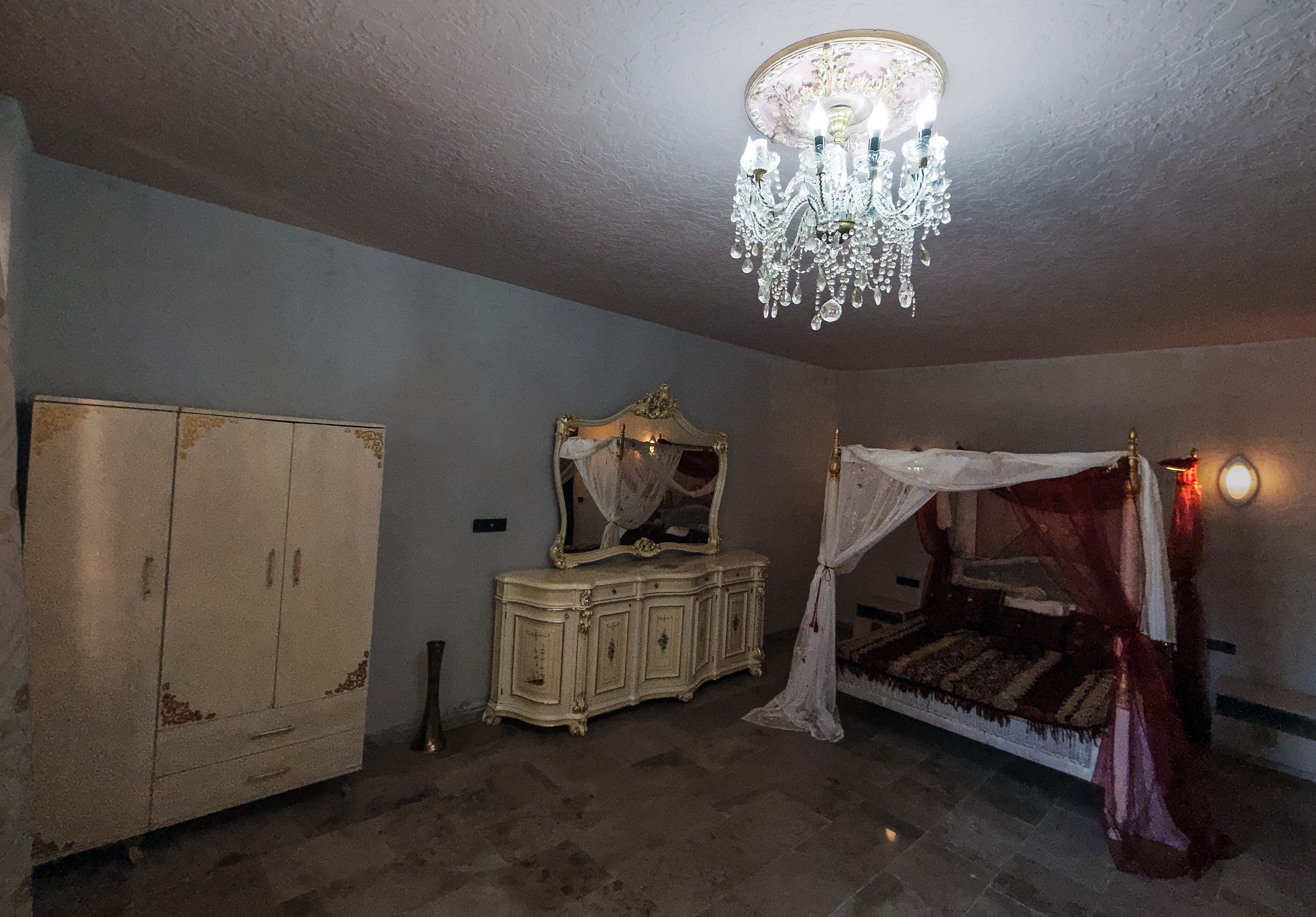 Un dormitorio con cama con dosel, un armario y una araña.
