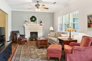 A living room with a fireplace, a ceiling fan, a sofa, a coffee table, and a rug. - Downtown 2 bedroom/2bath adorable, spacious bungalow (Hendersonville)