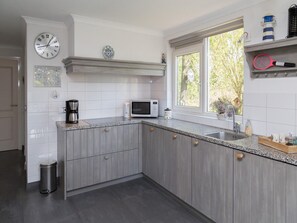 Cocina moderna con microondas, cafetera y ventana con vista a árboles.