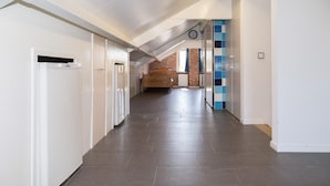 Un corridoio con una ventola a soffitto, un orologio e un letto in lontananza.