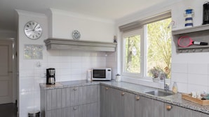Una cucina moderna con microonde, macchina del caffè e una finestra vista verde.