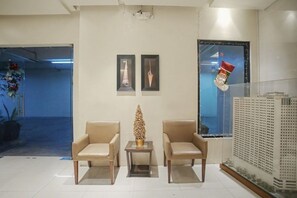 Eine Lobby mit zwei Ledersesseln, einem kleinen Tisch und einer Zierpflanze.