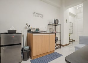 A compact kitchen with a refrigerator, microwave, and wooden cabinets. - Cozy Stay at Winland Tower Residences (Quezon City)