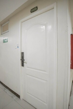 A white door with a keypad lock, a small window above it, and a sign on the wall to the left. - Cozy Stay at Winland Tower Residences (Quezon City)