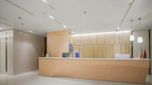 Un comptoir d’accueil au design moderne, une horloge au mur et un intérieur épuré et minimaliste.