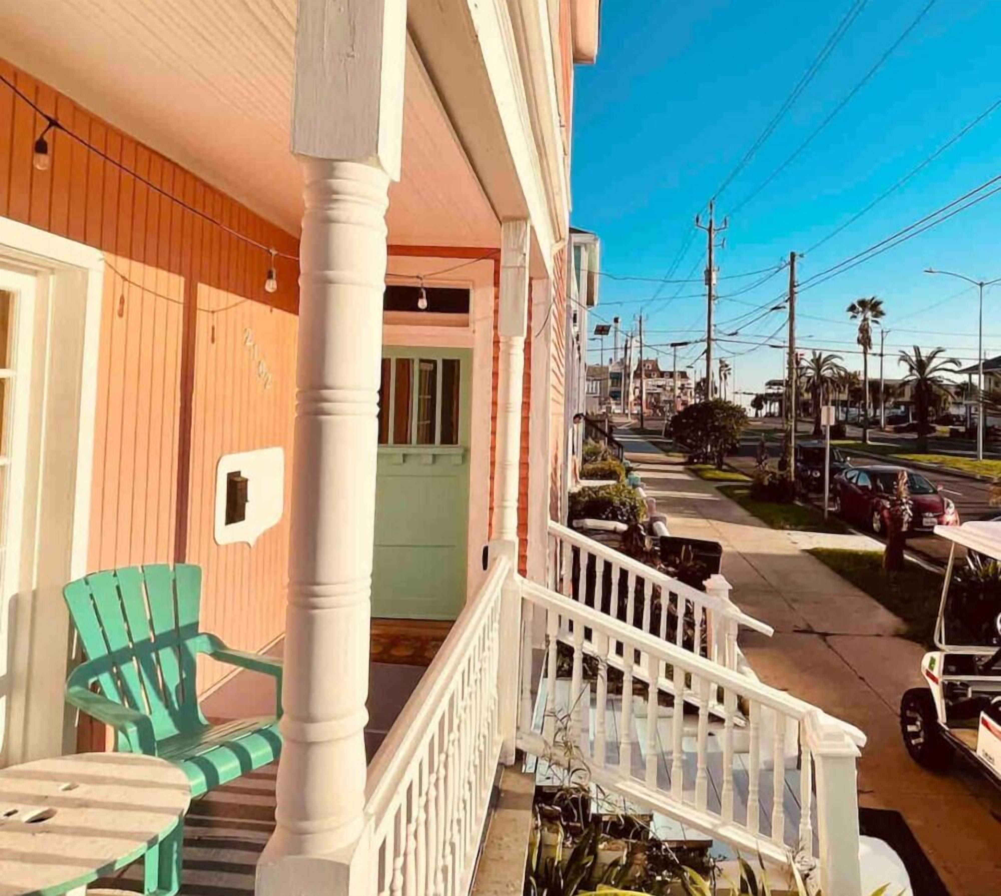 A porch with a white railing, a green chair, and a table.