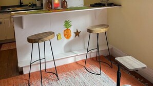 A kitchen with a bar area, a television, and a pineapple-themed wall decoration. - Pineapple By the Sea (Galveston)