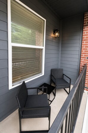 Ein Balkon mit zwei Stühlen, einem kleinen Tisch und einem Fenster mit Rollläden.