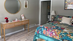 Een slaapkamer met een bed, een kaptafel, een spiegel en een deur naar een andere kamer.