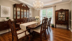 Une salle à manger avec une table en bois, des chaises, un lustre et un buffet.