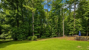 Un espace extérieur verdoyant, avec des arbres et un parasol bleu.