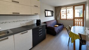 Eine kompakte Küche mit Kaffeemaschine, einer Couch und einem Esstisch mit Stühlen.