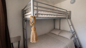 Ein Stockbett mit Seil- und Makramee-Dekoration, ein Nachttisch und eine Lampe.