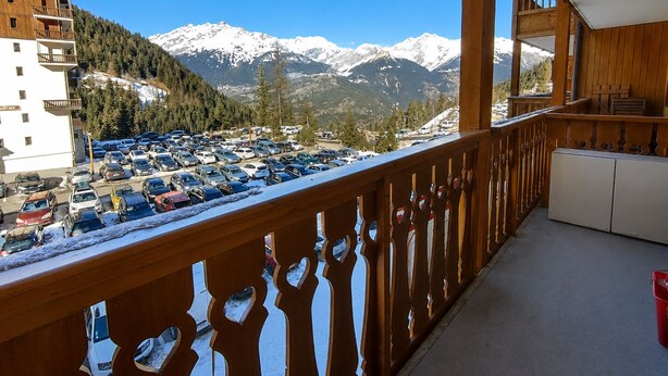 Ein Balkon mit Blick auf ein verschneites Gebirge und einen Parkplatz.