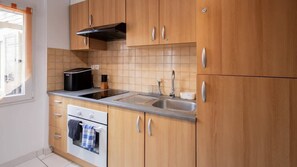Une cuisine avec des meubles de rangement en bois, une cuisinière, un évier et une fenêtre.