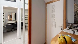 Une salle de bain moderne avec un miroir, un lavabo et des toilettes. On y trouve une porte sur laquelle est inscrit le mot « RÊVE ».
