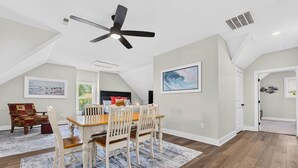 A dining area with a table, chairs, a ceiling fan, and artwork on the walls. - Spacious 4 BDR/3 BA pet friendly <10 min walk to beach + Hot Tub (Oak Island)