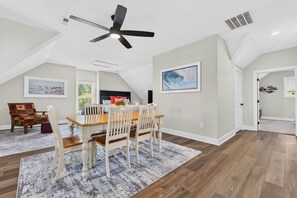 Ein Essbereich mit Tisch, Stühlen, einem Deckenventilator und Kunstwerken an den Wänden.