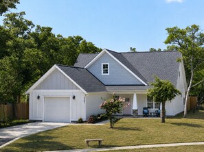 Einbungalow mit Garage, überdachter Veranda und kleinem Vorgarten.