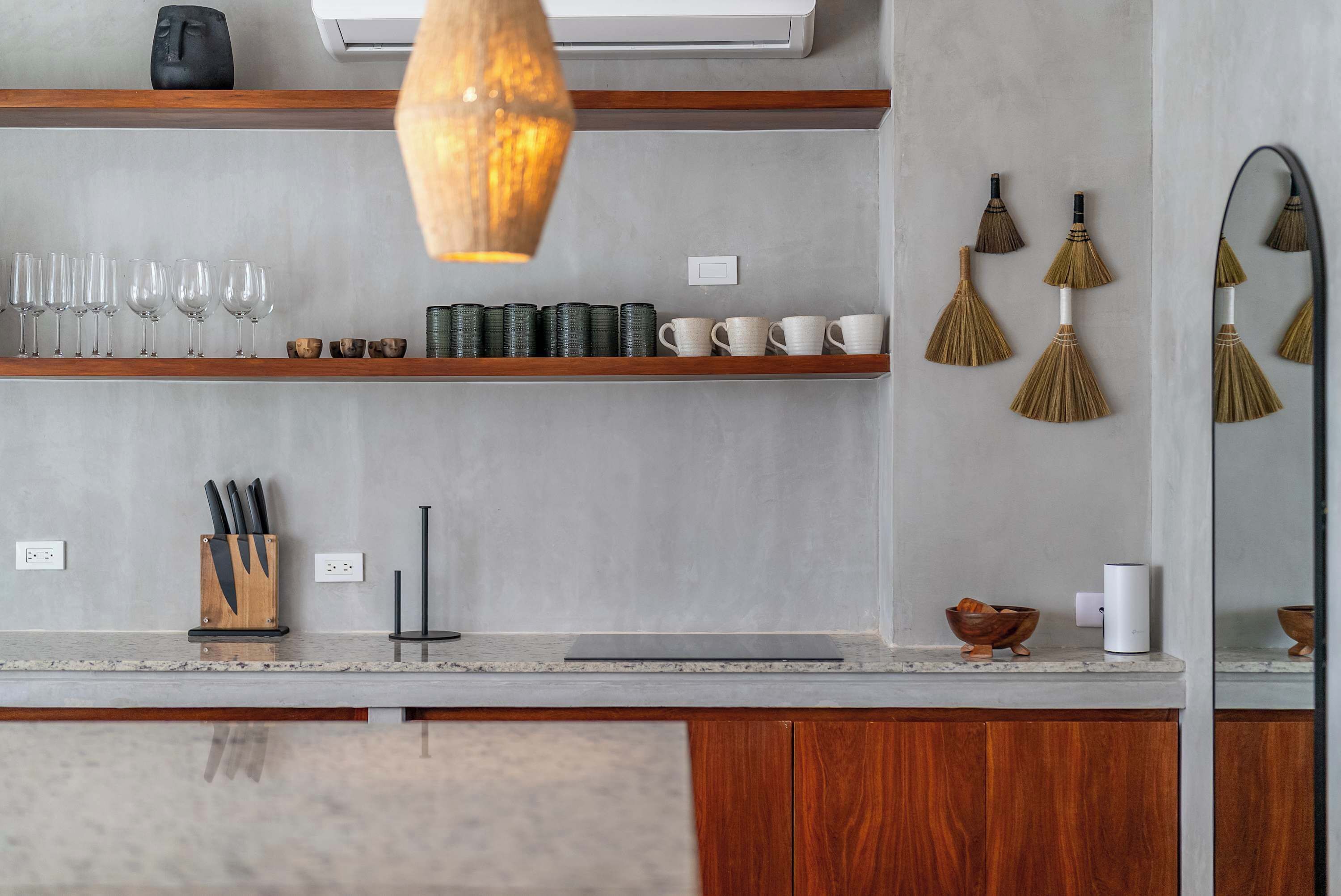 A kitchen with wooden shelves, a hanging light, and a mirror.