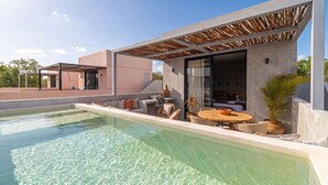 Uma área de piscina moderna, com piscina transparente, mobiliário de exterior e um terraço coberto.