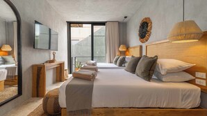 Quarto de hotel moderno com uma cama grande, uma televisão, uma cabeceira de madeira e vista para o exterior.