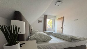 Ein Schlafzimmer mit Bett, Nachttisch, Lampe und einer Zimmerpflanze.
