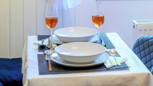 Una mesa dispuesta con platos blancos, fuentes, cubiertos y vasos con un líquido transparente, probablemente agua o una bebida sin alcohol.