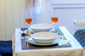 A table set with white plates, bowls, cutlery, and glasses of a clear liquid, likely water or a non-alcoholic beverage.