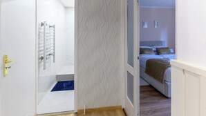 Una habitación con una cama, una puerta que da al baño y un papel tapiz decorado.